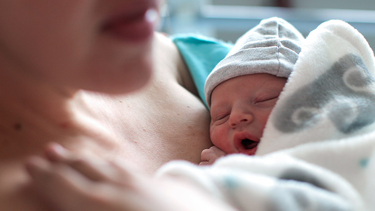 Vrouw met pasgeboren baby tegen de borst