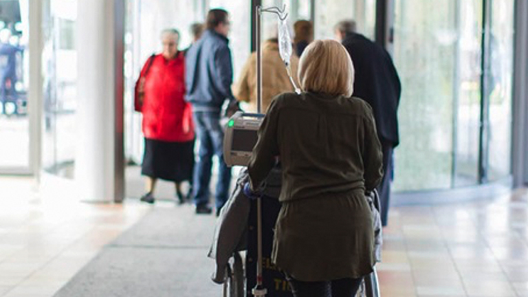 Vrouw duwt oma in rolstoel door ziekenhuis