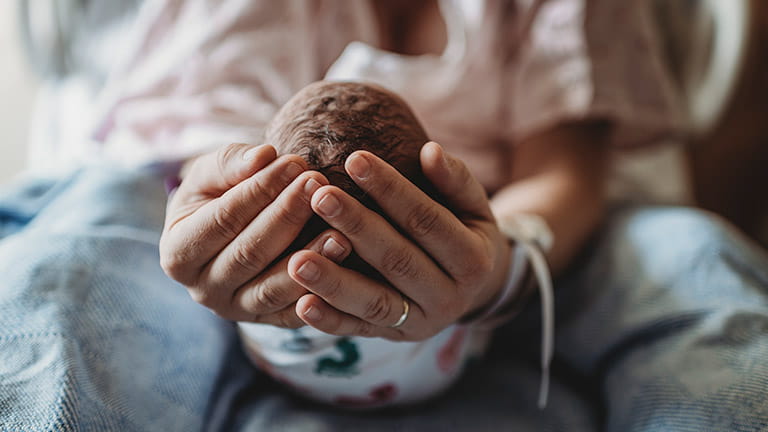 Vrouw houdt pasgeboren baby vast in haar handen