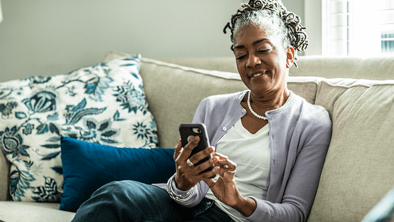 Vrouw zit met telefoon op de bank