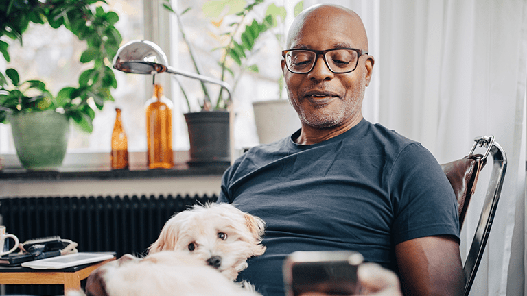 Man kijkt op telefoon met hondje op schoot