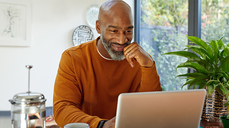 Man lachend achter laptop