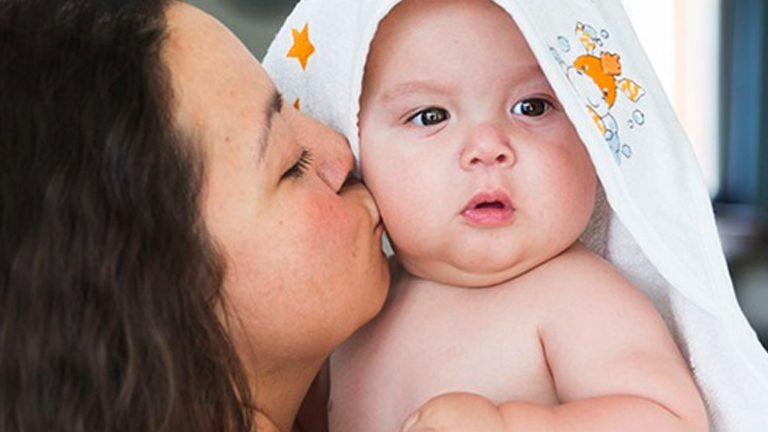 Moeder met kindje dat net uit bad is in badcape