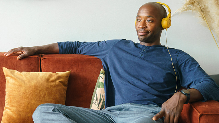 Man luistert muziek op de bank met headset op