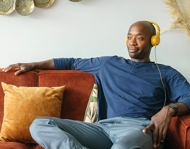 Jongen luistert muziek op de bank met koptelefoon op