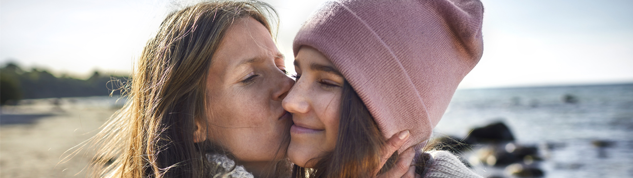 Moeder kust dochter op het strand