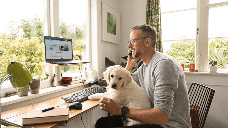 Man belt voor computer met hond op schoot